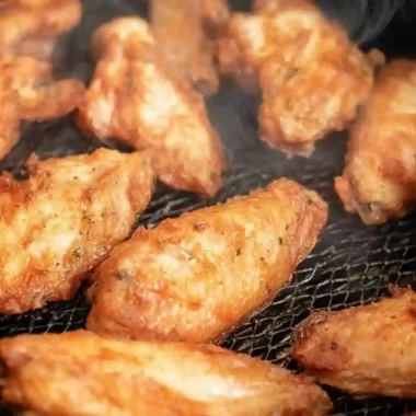 Crispy golden Air Fryer Chicken Wings cooking in an air fryer basket with steam rising, showing crunchy skin and juicy texture
