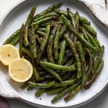 Crispy Air Fryer Green Beans in Just 10 Minutes 5 Crispy air fryer green beans served with lemon slices on a white plate