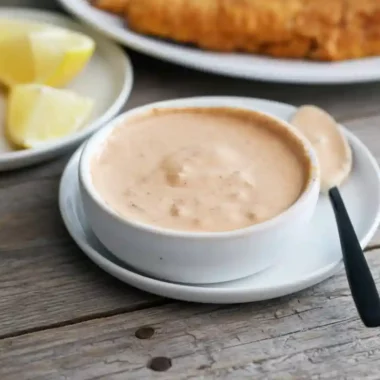 A creamy bowl of homemade dip shown in the Easy Remoulade Sauce Recipe, served with lemon wedges on the side.