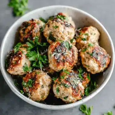 The Ultimate Turkey Meatballs Recipe 3 Close-up of savory Turkey Meatballs garnished with fresh parsley and grated cheese in a rustic bowl.