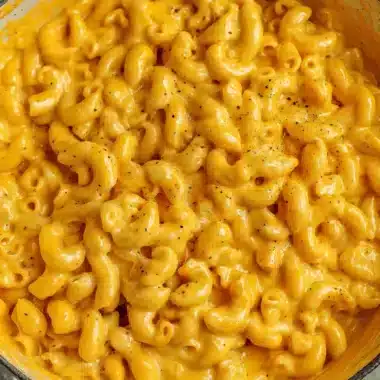 The Ultimate Easy Velveeta Mac and Cheese 3 A close-up, high-angle view of a generously portioned dish of creamy, golden Velveeta Mac and Cheese, topped with black pepper.