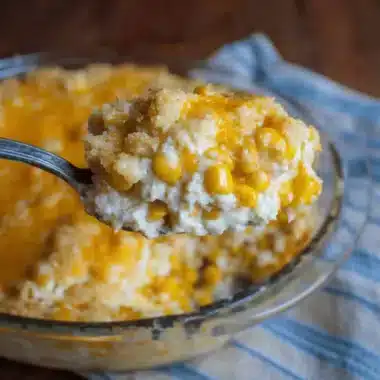 Easy Cream Cheese Corn Casserole: A Fantastic Side 4 Close-up of a spoonful of creamy, cheesy Cream Cheese Corn Casserole being lifted from a glass baking dish, showcasing golden-brown topping and melted cheese.