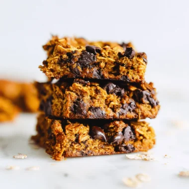 Ultimate Pumpkin Chocolate Chip Oatmeal Bars Recipe 4 Stack of three chewy Pumpkin Chocolate Chip Oatmeal Bars on a white marble surface.