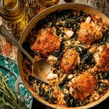Delicious Chicken and Wild Rice Casserole with crispy chicken, greens, and herbs in a rustic cast iron skillet.