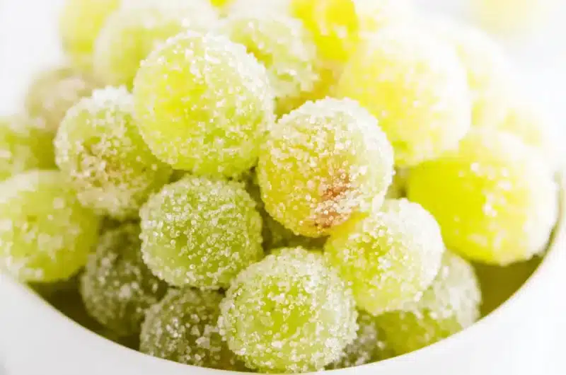 Bright close-up of sparkling, frosted green Sugared Champagne Grapes in a white bowl.