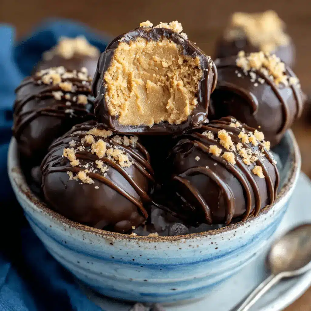 Appetizing close-up of chocolate-covered Peanut Butter Balls in a ceramic bowl, one cut open to reveal creamy filling.