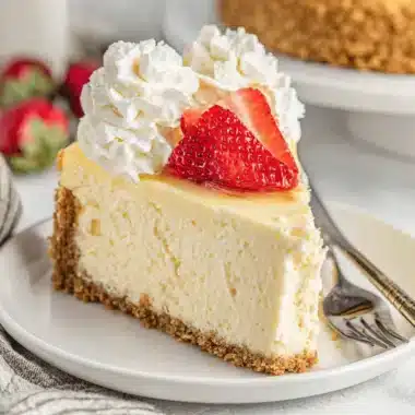 Classic strawberry cheesecake slice with glossy glaze and whipped cream, embodying the delicious cheesecake aesthetic.