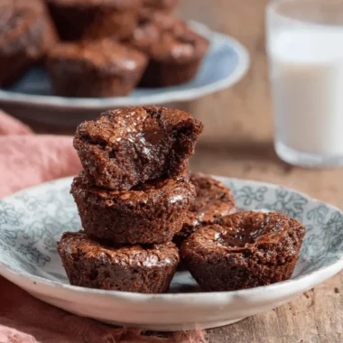 Stacked fudgy chocolate brownie bites on a rustic plate, revealing a gooey chocolate center.
