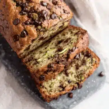 Freshly sliced, moist chocolate chip zucchini banana bread loaf resting on a slate board, highlighting the perfect crumb texture.