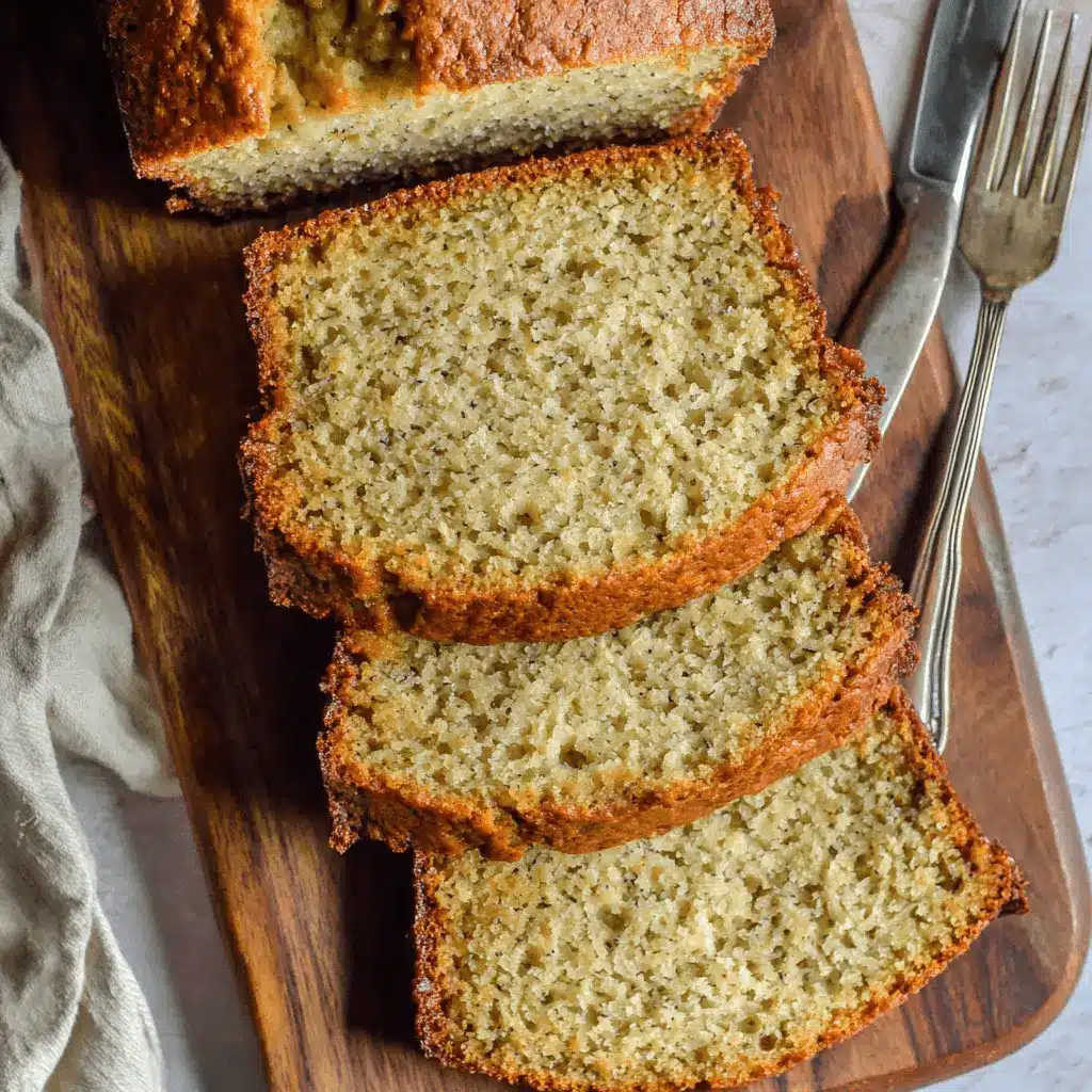 Overhead view of moist slices of freshly baked cake mix banana bread resting on a dark wooden cutting board with a vintage knife and fork.