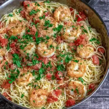 The Ultimate Shrimp Pasta Recipe: Quick & Delicious 3 Plump shrimp and thin spaghetti with tomatoes and parsley in a skillet, showcasing easy shrimp pasta recipes.
