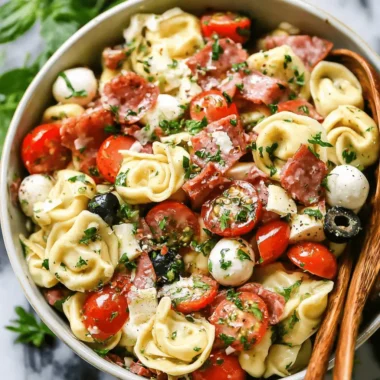 Hearty Italian tortellini pasta salad with salami, mini mozzarella, cherry tomatoes, and fresh herbs in a ceramic serving bowl.