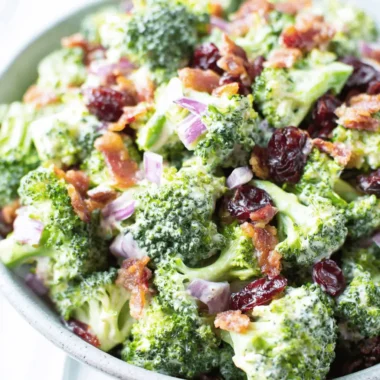 The Ultimate Broccoli Salad Recipe 3 Appetizing close-up of classic creamy **broccoli salad** featuring bacon crumbles and dried cranberries.