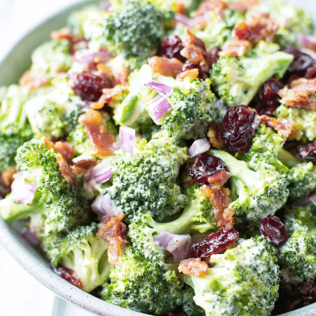 Appetizing close-up of classic creamy **broccoli salad** featuring bacon crumbles and dried cranberries.