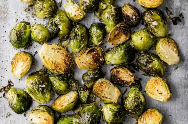 Highly detailed image of perfectly seasoned and caramelized Roasted Brussels Sprouts scattered on a light background.