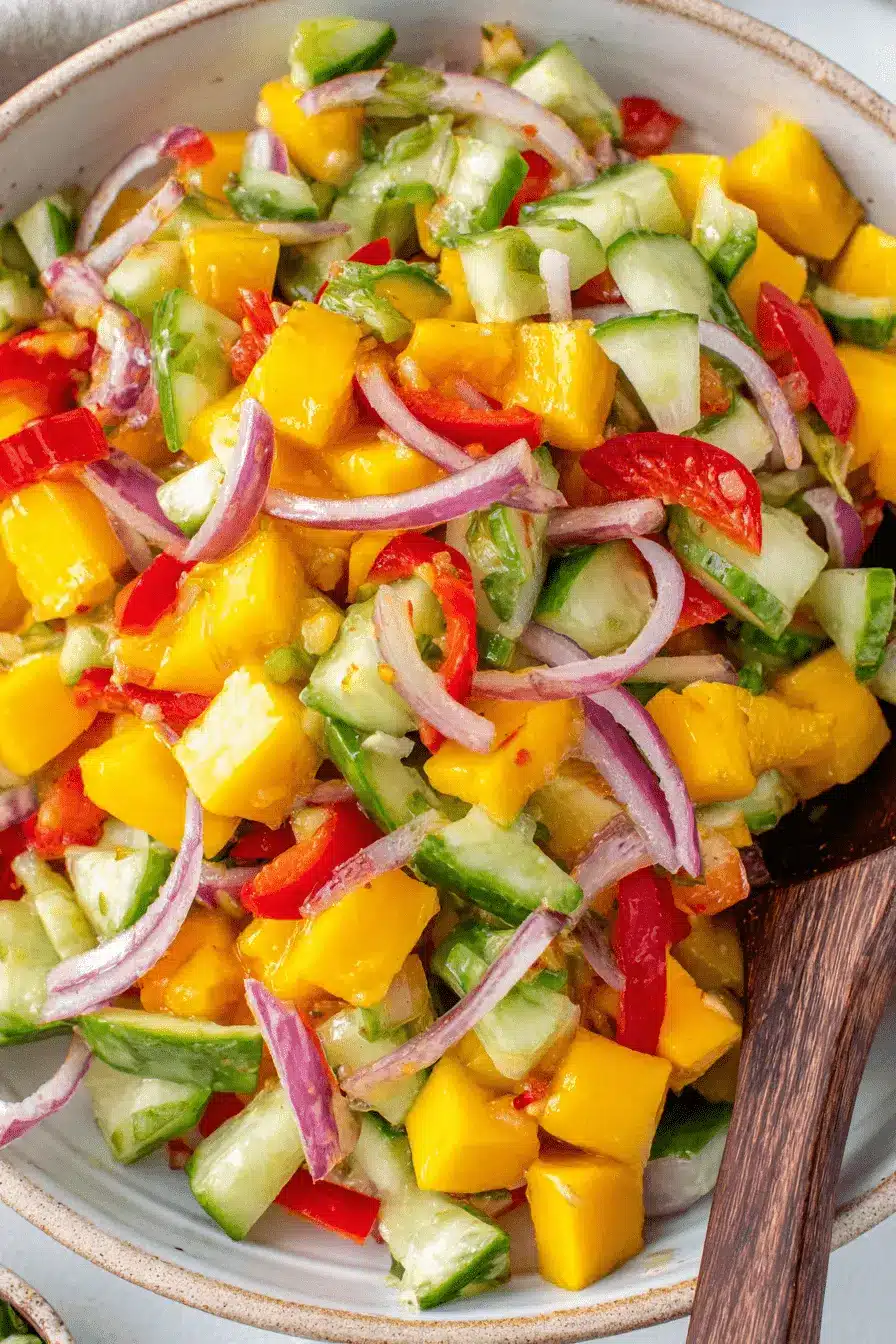 Ultimate Mango Salad Recipe: Vibrant & Refreshing 2 Close-up of a vibrant, chunky tropical mango salad with cucumber, red onion, and chili served in a rustic stoneware bowl.