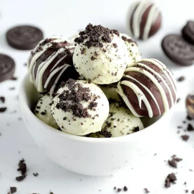 The Ultimate Easy No-Bake Oreo Balls 3 Delicious white and dark chocolate Oreo Balls piled high in a white bowl with scattered Oreo cookies.