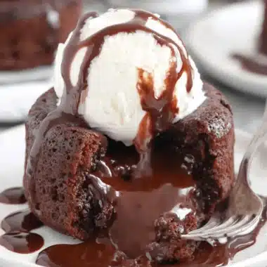 Amazing Molten Chocolate Lava Cake Recipe 4 Close-up of a decadent Molten Chocolate Lava Cake, broken open to reveal the rich, flowing chocolate center, served with vanilla ice cream and chocolate drizzle.