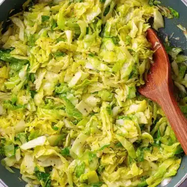 Wonderful Napa Cabbage Recipes: Quick & Easy Stir-fry 4 Overhead shot of sautéed napa cabbage and seasoning in a dark non-stick skillet, illustrating easy napa cabbage recipes.