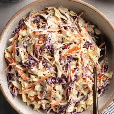 Amazing Classic Coleslaw: Never Soggy Again! 3 Top-down view of creamy tri-color Classic Coleslaw with shredded carrots and purple cabbage in a rustic ceramic bowl.