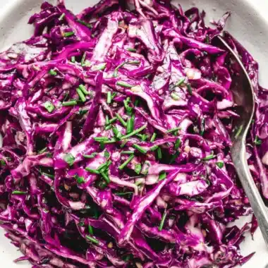 Vibrant Red Cabbage Slaw: Quick & Easy Recipe 3 Overhead close-up of vibrant red cabbage slaw in a ceramic bowl, garnished with green chives and ready to eat.