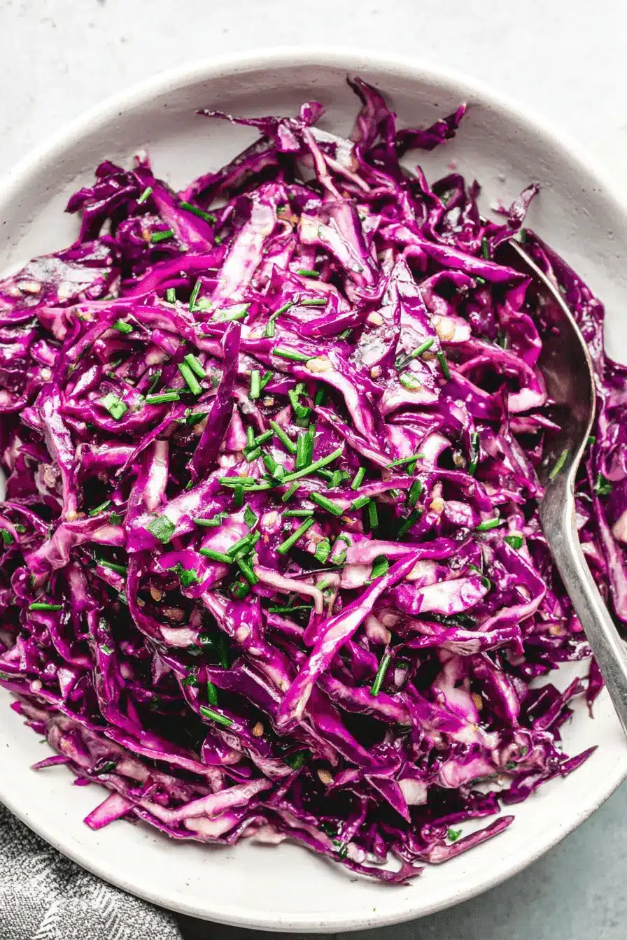 Vibrant Red Cabbage Slaw: Quick & Easy Recipe 2 Overhead close-up of vibrant red cabbage slaw in a ceramic bowl, garnished with green chives and ready to eat.