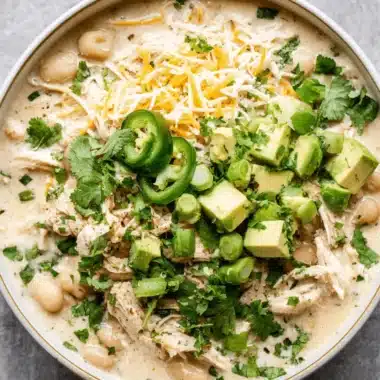 The Ultimate Foolproof White Chicken Chili Slow Cooker 3 A close-up, overhead view of white chicken chili slow cooker, topped with fresh avocado, cilantro, and shredded cheese.