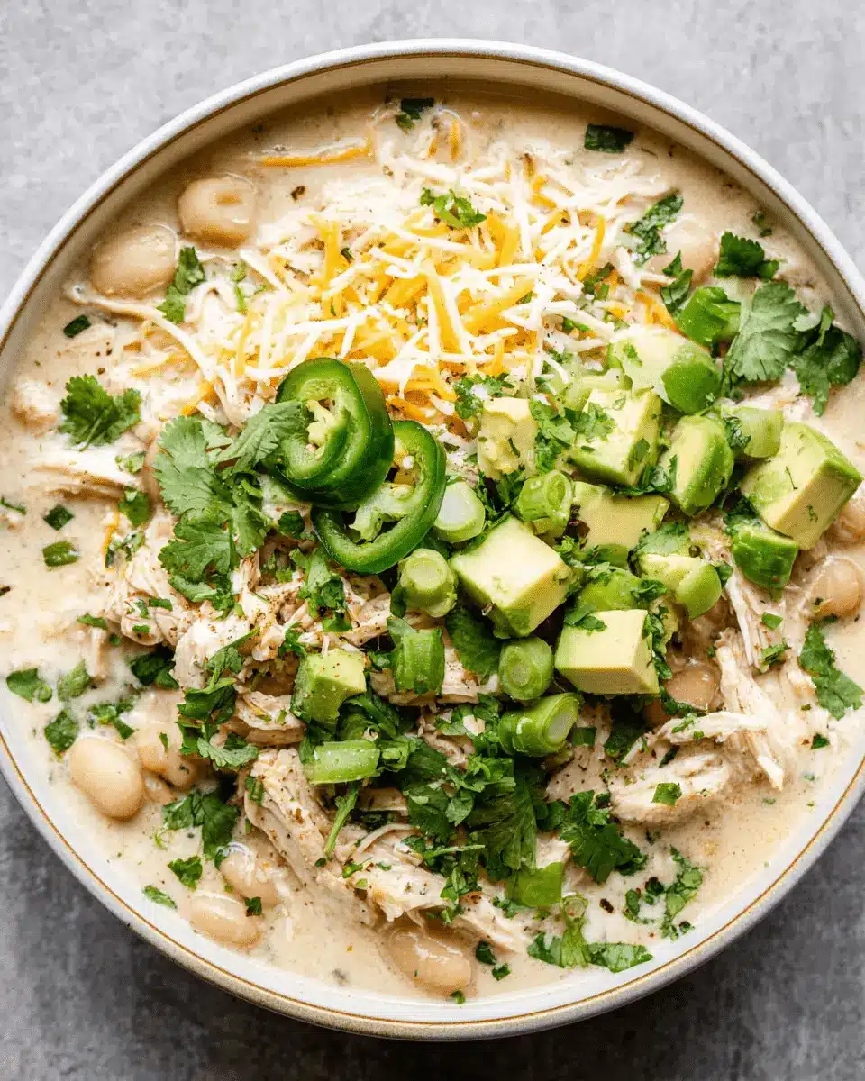 The Ultimate Foolproof White Chicken Chili Slow Cooker 2 A close-up, overhead view of white chicken chili slow cooker, topped with fresh avocado, cilantro, and shredded cheese.