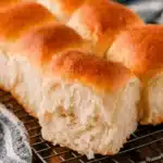 Freshly baked, golden Pull Apart Sourdough Dinner Rolls cooling on a wire rack, highlighting the soft interior crumb.