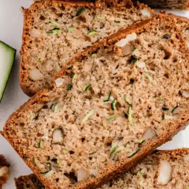 The Ultimate Sourdough Zucchini Bread Recipe 4 Sliced loaf of moist Sourdough Zucchini Bread with visible walnuts and shredded zucchini flecks, photographed from overhead.