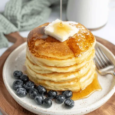 Ultimate Sourdough Discard Pancakes 3 Stack of fluffy Sourdough Discard Pancakes drizzled with golden syrup, topped with melting butter and fresh blueberries.