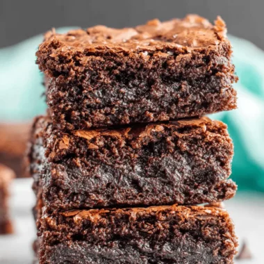 Amazing Sourdough Brownies with Crackly Tops 3 Close-up stack of three fudgy Sourdough Brownies with a crackled top and a sprinkle of sea salt.