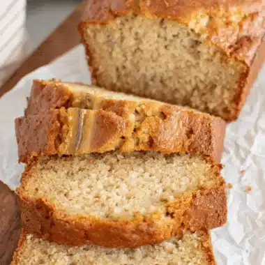 Fantastic Sourdough Banana Bread Recipe 3 Golden brown, moist slices of Sourdough banana bread on a dark cutting board, highlighting the tender crumb and visible banana pieces.