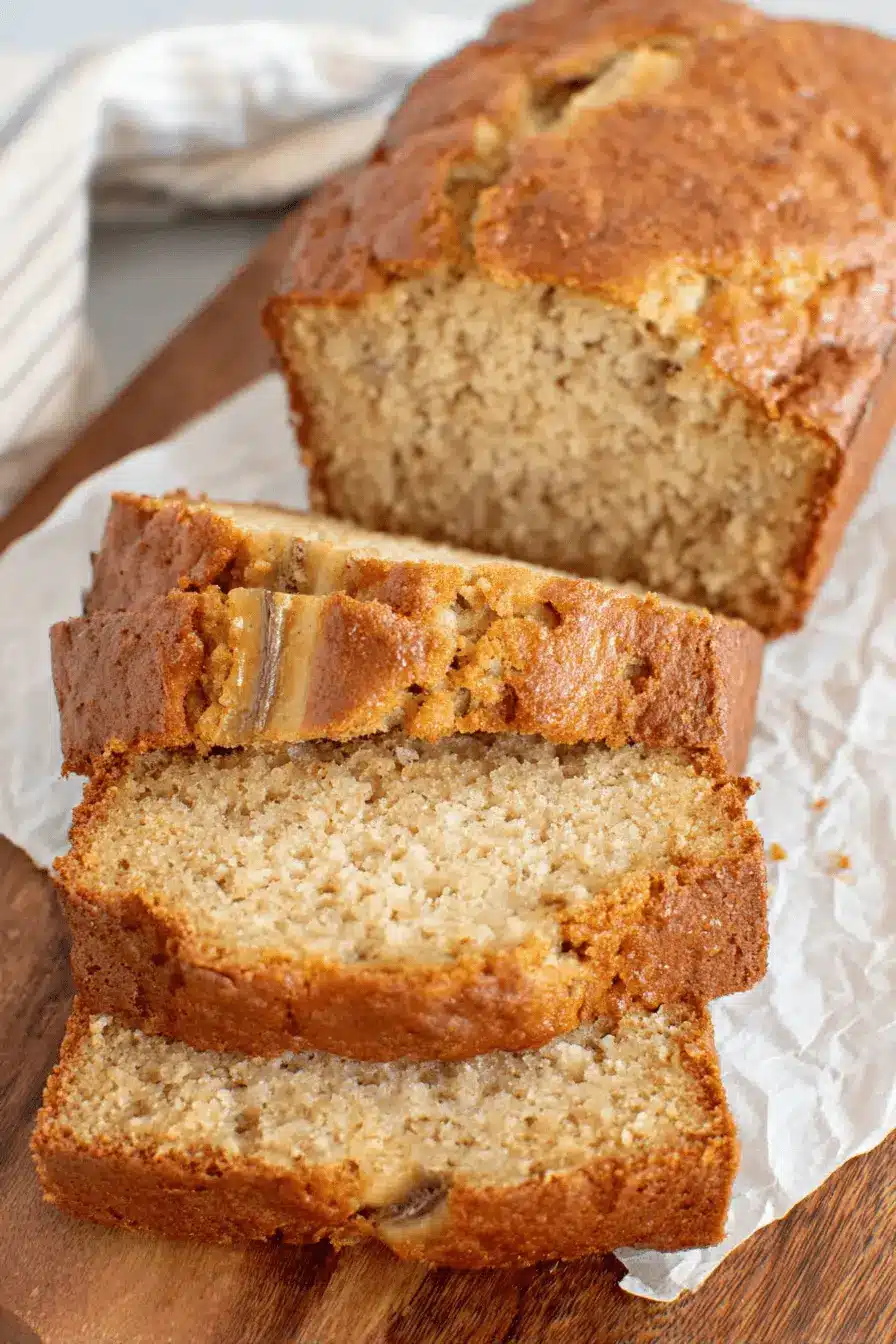 Fantastic Sourdough Banana Bread Recipe 2 Golden brown, moist slices of Sourdough banana bread on a dark cutting board, highlighting the tender crumb and visible banana pieces.