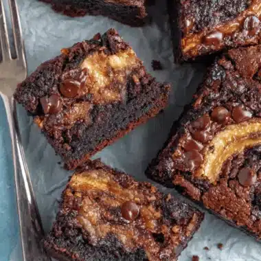 Ultimate Foolproof Banana Bread Brownies 3 Top-down view of fudgy dark chocolate banana bread brownies cut into squares on parchment paper.