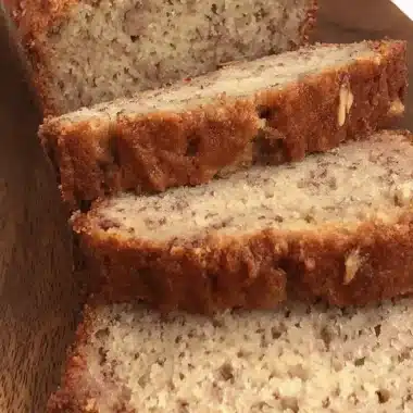 Amazing Eggless Banana Bread: Easy & Moist 4 A freshly sliced loaf of moist, golden-brown eggless banana bread presented on a rustic wooden cutting board.