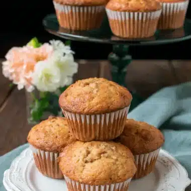 Amazing Easy Banana Bread Muffins 3 Stack of freshly baked, golden-brown banana bread muffins easy recipe on a rustic white plate.