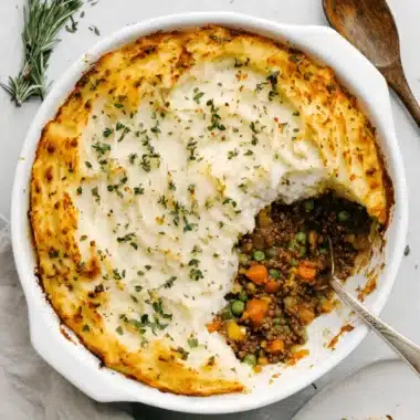 Ultimate Shepherds Pie Casserole: Easy & Delicious 4 Rustic, homemade shepherds pie casserole in an oval white dish, topped with golden mashed potatoes and fresh herbs, ready to be served.