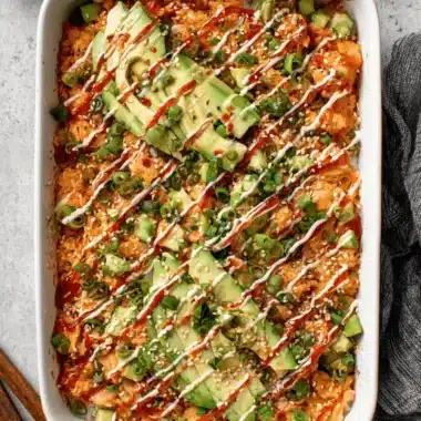 Foolproof Salmon Sushi Bake Recipe: Ultimate Comfort 3 Top-down shot of a fully garnished, ready-to-eat salmon sushi bake recipe topped with avocado, sesame seeds, and spicy mayo drizzle.