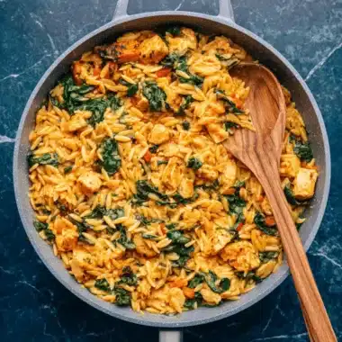 Amazing One-Pot Creamy Cajun Chicken Orzo 4 Creamy cajun chicken orzo dish with spinach and red bell peppers cooked in a gray non-stick skillet.