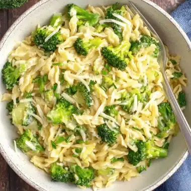 Ultimate One-Pot Broccoli Cheddar Orzo 3 Close-up of a comforting bowl of creamy broccoli cheddar orzo sprinkled with fresh herbs.