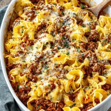 The Ultimate Sour Cream Beef Noodle Casserole 4 Overhead view of a bubbling sour cream beef noodle casserole in a white ceramic dish, garnished with fresh parsley.