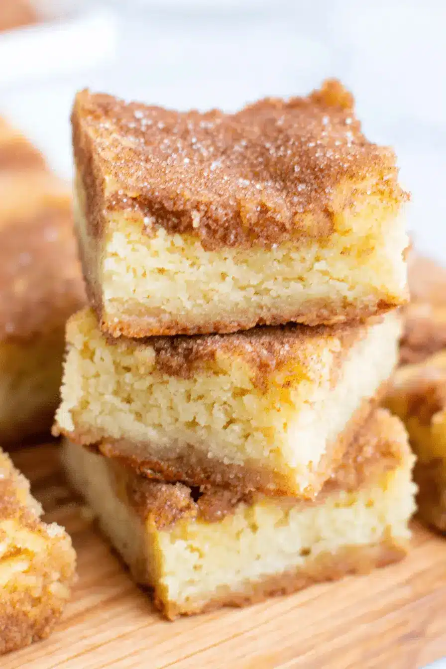 Quick & Easy Cinnamon Sugar Blondies: Irresistibly Chewy 2 Stacked homemade Cinnamon Sugar Blondies on a wooden cutting board, showing the cinnamon swirl topping and caramelized edges.