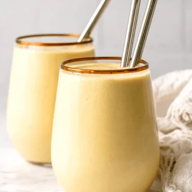 The Ultimate Homemade Korean Banana Milk 4 Creamy, frothy korean banana milk smoothie served in a tall glass with a copper rim and silver metal straws.