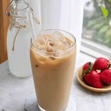 The Ultimate Milk Tea Recipe for Perfect Homemade Sips 4 Close-up of a refreshing iced milk tea beverage served in a tall glass, complemented by fresh ripe strawberries and natural daylight.