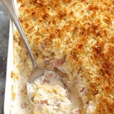 Quick & Easy Chicken Cordon Bleu Casserole 4 Close-up of a creamy chicken cordon bleu casserole with a golden breadcrumb topping being served with a vintage spoon.