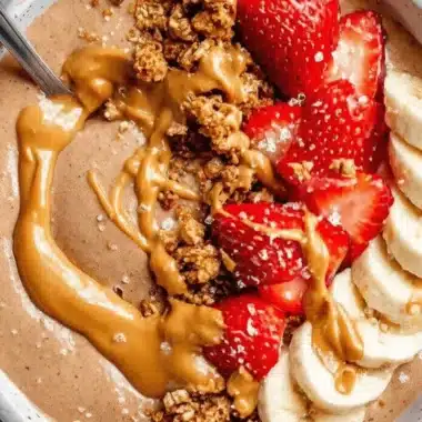 Amazing Chocolate Peanut Butter Yogurt Bowl 3 Close-up of a chocolate or peanut butter yogurt bowl generously topped with strawberries, bananas, granola, and a thick peanut butter drizzle, ready to eat.