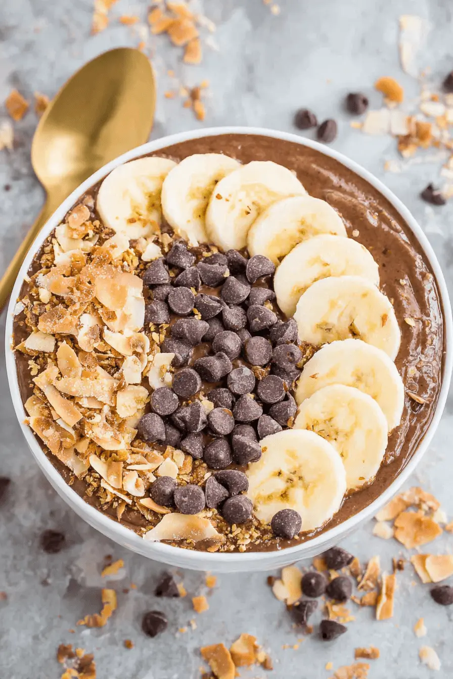 The Ultimate Chunky Monkey Smoothie Bowls 2 Overhead shot of thick chocolate Chunky Monkey Smoothie Bowls topped with banana slices, dark chocolate chips, and toasted coconut flakes.