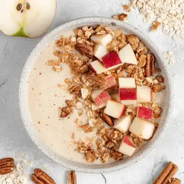 Wonderful Apple Pie Smoothie Bowl: Quick & Cozy 3 Close-up, overhead view of a rustic Apple Pie Smoothie Bowl garnished with fresh diced apples, pecans, and cinnamon sticks.