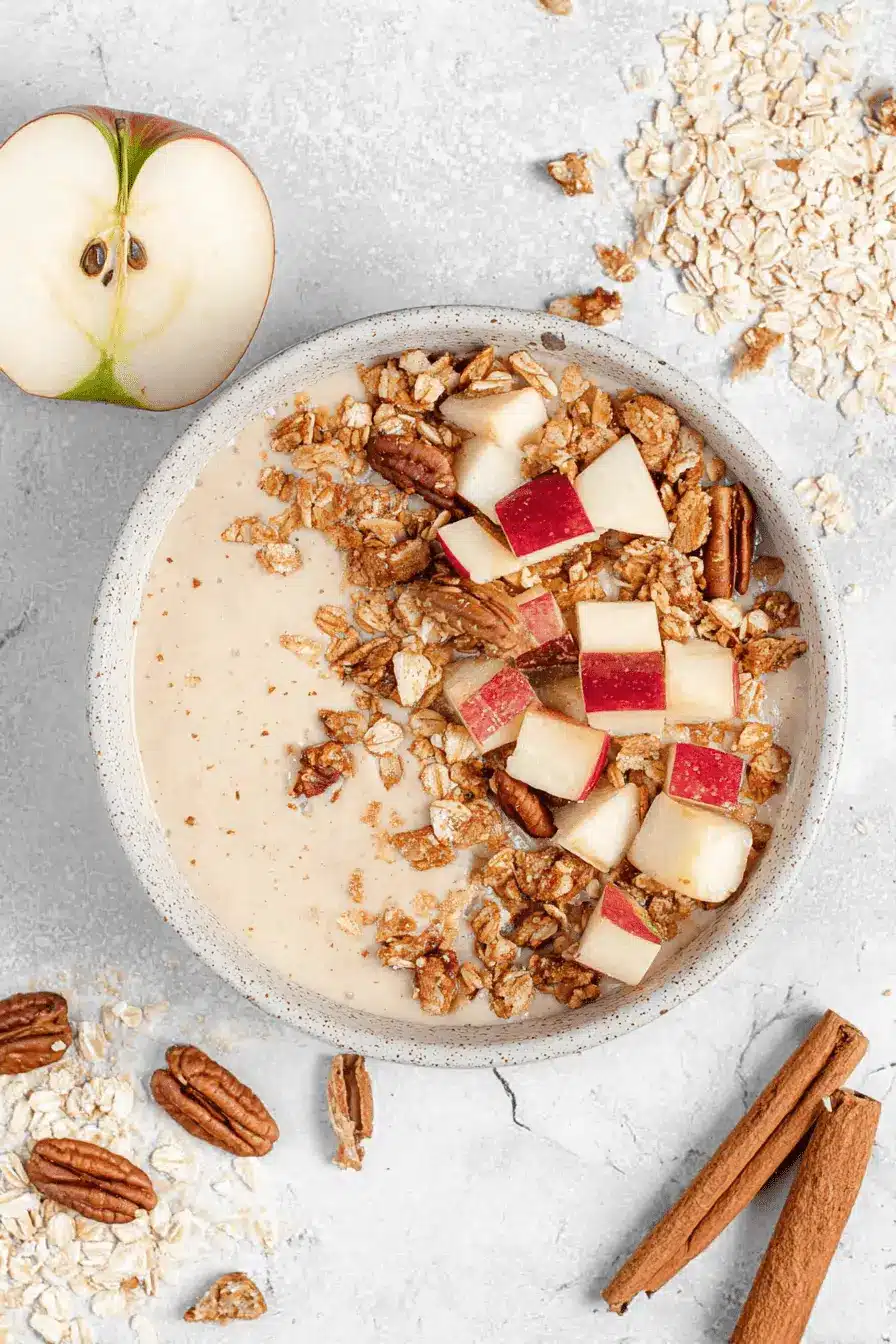 Wonderful Apple Pie Smoothie Bowl: Quick & Cozy 2 Close-up, overhead view of a rustic Apple Pie Smoothie Bowl garnished with fresh diced apples, pecans, and cinnamon sticks.